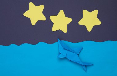 Kağıt okyanusta origami köpekbalığı sahnesi yıldızlı gece gökyüzünün arka planına karşı. Çocukların yaratıcılığı