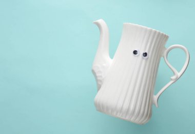 Mavi zemin üzerinde gözleri olan seramik çaydanlık