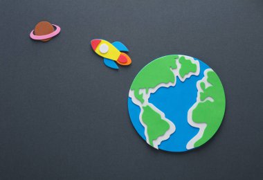 El yapımı, çocuk sanatı. Gri arka planda roketi olan dünya gezegeni. Uzay keşfi