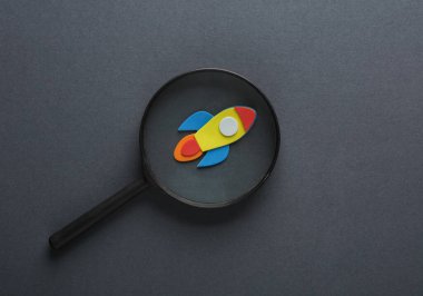 Gri arka planda roket olan büyüteç. Girişim, iş konsepti