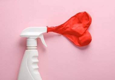 Yaratıcı aşk ve temizlik düzeni. Pembe arka planda kalp şeklinde balon olan sprey şişesi.