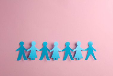 Kağıt kesiği, pembe arka planda el ele tutuşan insanlar zinciri. Birlik kavramı