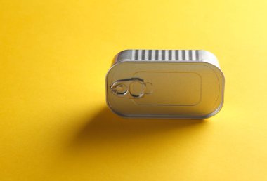 Sarı arka planda mühürlü teneke kutu.