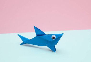 Pembe arka planda gözleri olan Origami köpekbalığı. Yaratıcı yerleşim