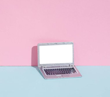 Pembe arka planda beyaz ekranlı minyatür bir laptop. Yaratıcı minimalist yerleşim