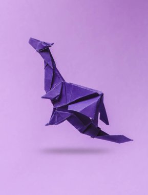 Origami ejderhası mor arka planda uçuyor