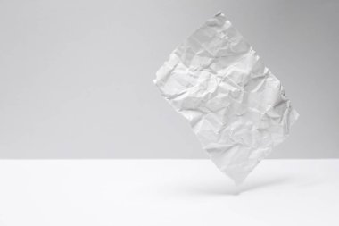 Gri-beyaz arka planda buruşmuş kağıt tabakası yükseliyor.