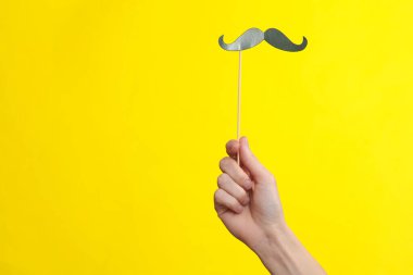 Sarı arka planda kadın eli olan kağıt kesiği bıyıklı. Babalar günü, parti konsepti.