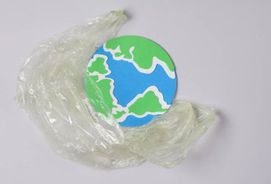 Kirlilik, ekolojik konsept. Gri arkaplanlı plastik çantalı dünya modeli