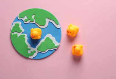 Pembe arka planda plastik ördekleri olan dünya gezegeni..