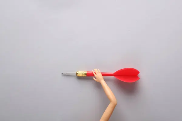 Puppet hand holding darts on gray background