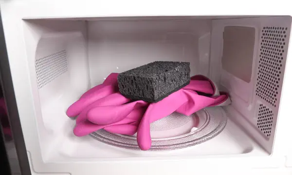 Microwave with cleaning gloves and a sponge. Cleaning in the kitchen concept.