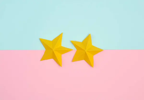 Two origami paper stars on pink blue pastel background. Service rating