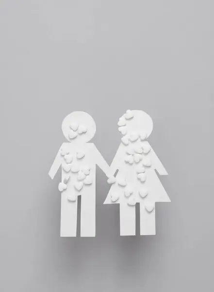 Family medicine. Paper cut man and woman with heart shaped pills on gray background