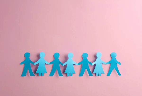 Paper cut chain of people holding hands on a pink background. Unity concept