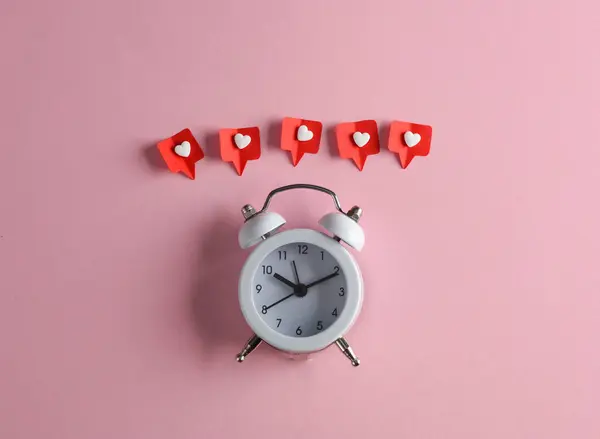 Alarm clock with Social media likes on pink background. Creative minimal layout