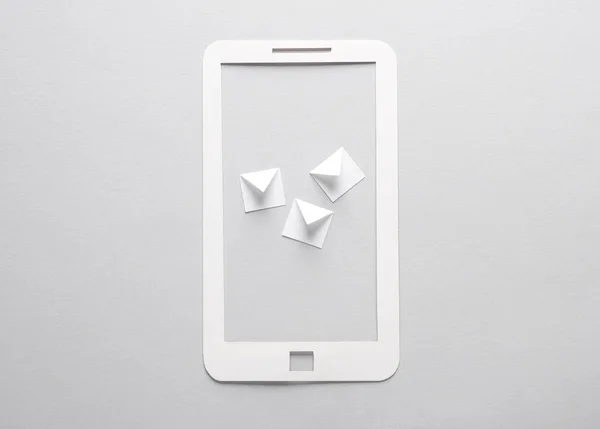 Paper-cut smartphone with envelopes on gray background.