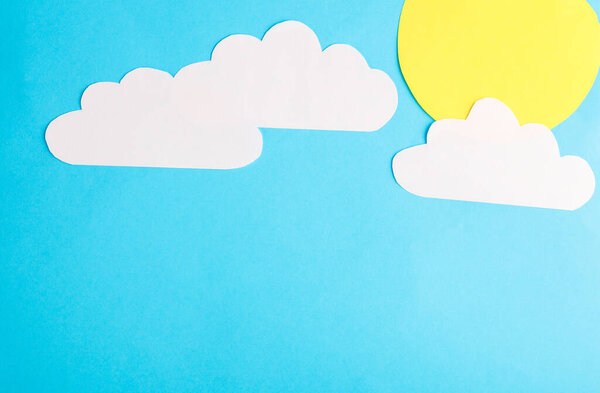 Paper cut clouds with sun on blue background