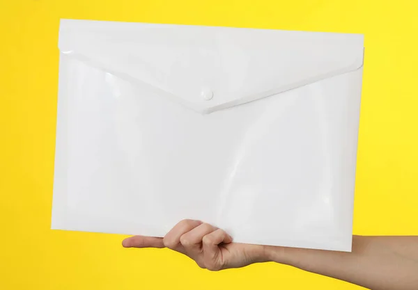 Weibliche Hand Hält Eine Weiße Plastikmappe Auf Gelbem Hintergrund — Stockfoto
