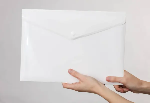 Γυναικείο Χέρι Που Κρατά Ένα Λευκό Πλαστικό Φάκελο Γκρι Φόντο — Φωτογραφία Αρχείου