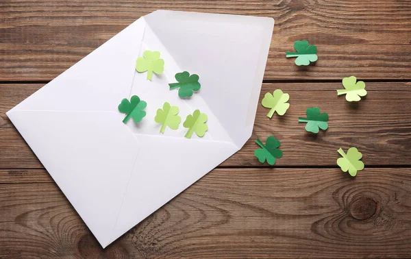 stock image St. patrick's day invitation. Envelope with clover leaves on wooden background. Flat lay