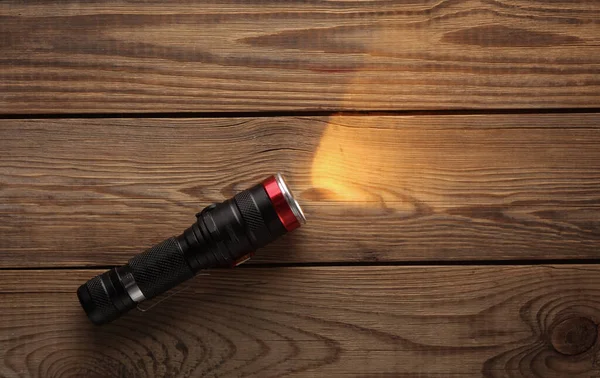 Tahta bir masanın üzerindeki parlak el feneri de dahil.