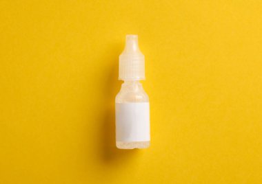 Sarı arka planda bir şişe göz damlası