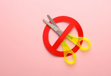 Pembe arka planda yasak işareti olan makas.