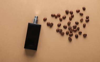 Kahverengi arka planda kahve çekirdekleri olan parfüm şişesi.