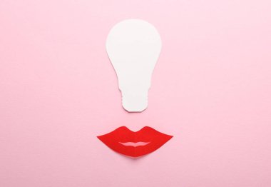 Yaratıcı bir fikir. Pembe arka planda ampullü kağıt dudaklar.