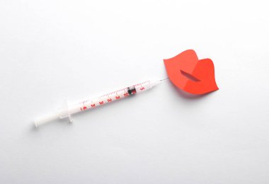 Dudak büyütme prosedürü. Kağıt dudaklar ve beyaz arka planda bir şırınga. Yaratıcı düzen, güzellik konsepti