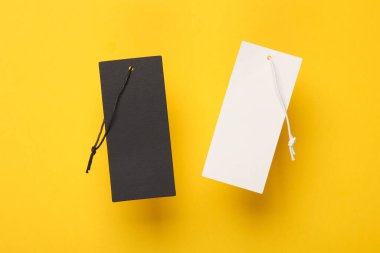 Beyaz ve siyah Blank giyim fiyat etiketleri veya etiketleri sarı arka planda dizgileri olan modeller. Satış, alışveriş konsepti.