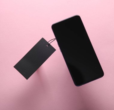Akıllı telefon ve siyah kuru giyim etiketi ya da pembe arka planda etiketi. Satış, online alışveriş konsepti. Üst görünüm