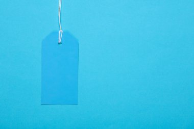 Mavi boş giyim etiketi ya da mavi arka planda iple etiketlenmiş maket modeli. Satış, alışveriş konsepti. Üst görünüm