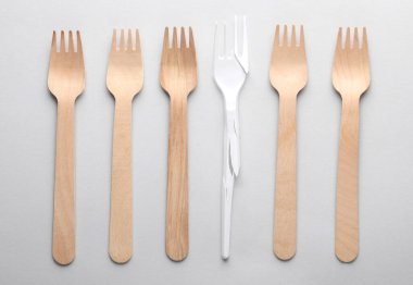 Kırık plastik çatal ve gri arka planda tahta çatallar. Plastiksiz, geri dönüşümlü, ekolojik konsept