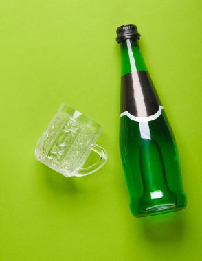 Yeşil arka planda bir şişe yeşil İrlanda birası ve bira bardağı. Üst görünüm