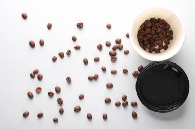 Gri arka planda kahve çekirdekleri olan beyaz karton bardaklar. Üst görünüm