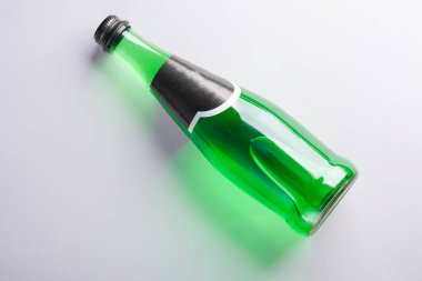 Gri arka planda bir şişe yeşil İrlanda birası. Üst görünüm