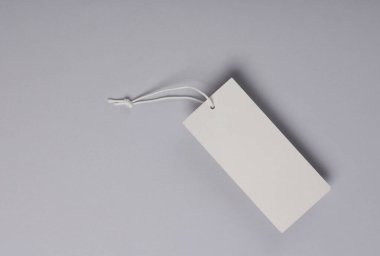 Beyaz boş giyim etiketi ya da gri arka planda ipe sahip etiket modeli. Satış, alışveriş konsepti. Üst görünüm