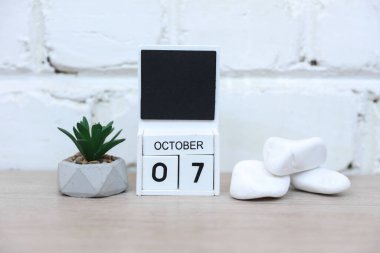 Tahta takvim ve tarihi Ekim 07. Masanın üstüne tuğla duvar arkası. Teslim tarihi, planlama, iş konsepti