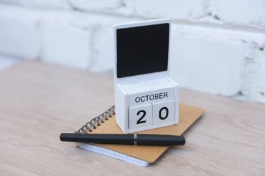 20 Ekim tarihli ahşap takvim ve duvara dayalı defter. Teslim tarihi, planlama, iş konsepti