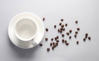 Gri arka planda kahve çekirdekleri olan seramik kahve fincanı. Üst görünüm