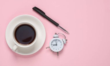 Bir fincan çay ya da çalar saat ve pembe arka planda bir kalem. Kahve molası. Üst görünüm