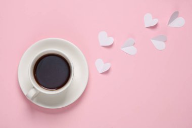 Bir fincan çay ya da pembe arka planda kalpleri olan bir kahve. Üst görünüm