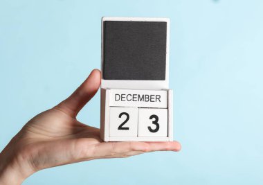 23 Aralık tarihli ahşap takvim, mavi arka planda izole edilmiş.