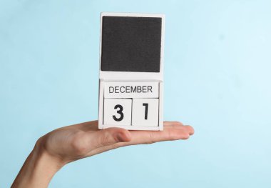 31 Aralık tarihli ahşap takvim, mavi arka planda izole edilmiş.