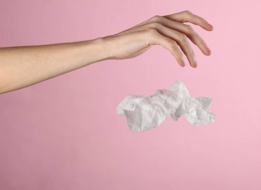 Pembe arka planda buruşuk bir peçete fırlatıyor.