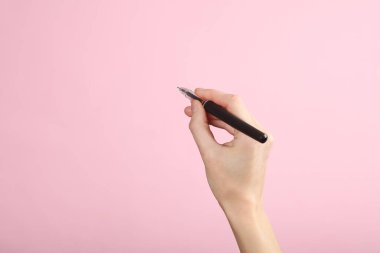 Kadın eli pembe arka planda kalemle yazıyor. Tasarım şablonu