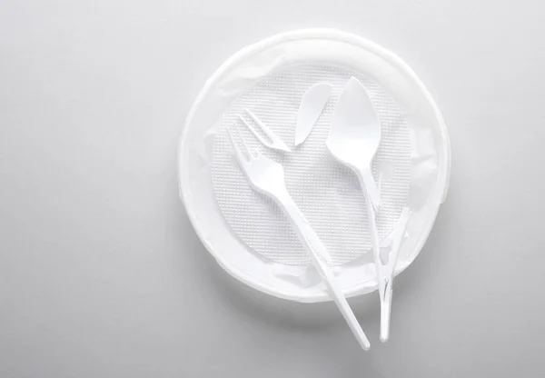 Broken plastic plate, fork and spoon on a gray background. Stop plastic pollution, recycling, eco concept
