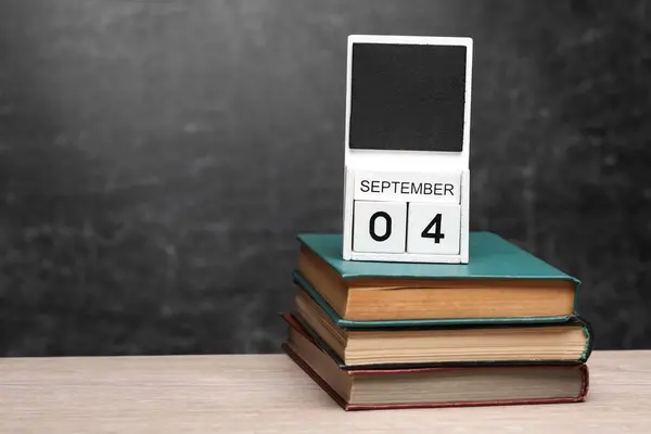 Calendar with september 04 date and books on table against chalk board background